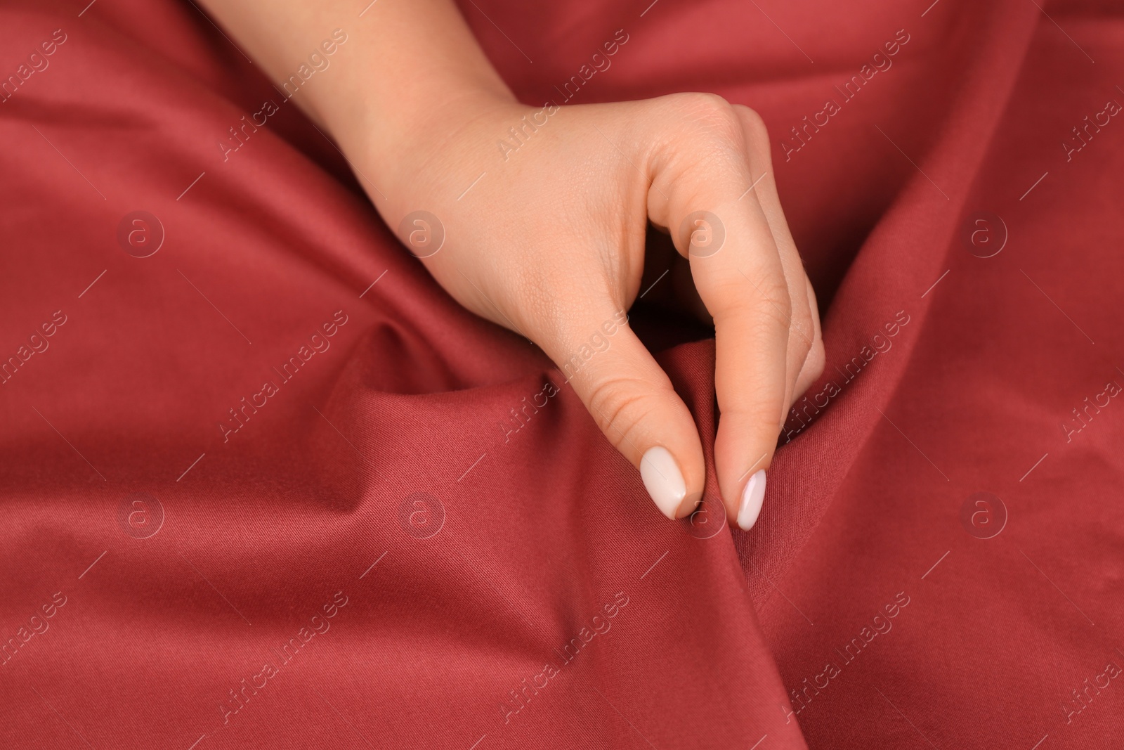 Photo of Woman touching smooth dark red fabric, closeup