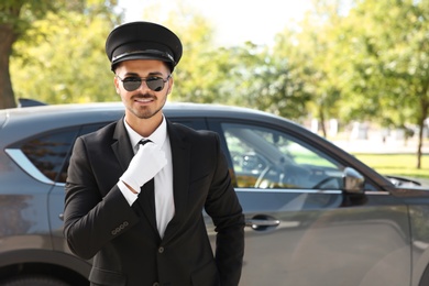 Photo of Young handsome driver standing near luxury car. Chauffeur service