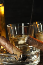 Photo of Cigars, ashtray and whiskey on table, closeup