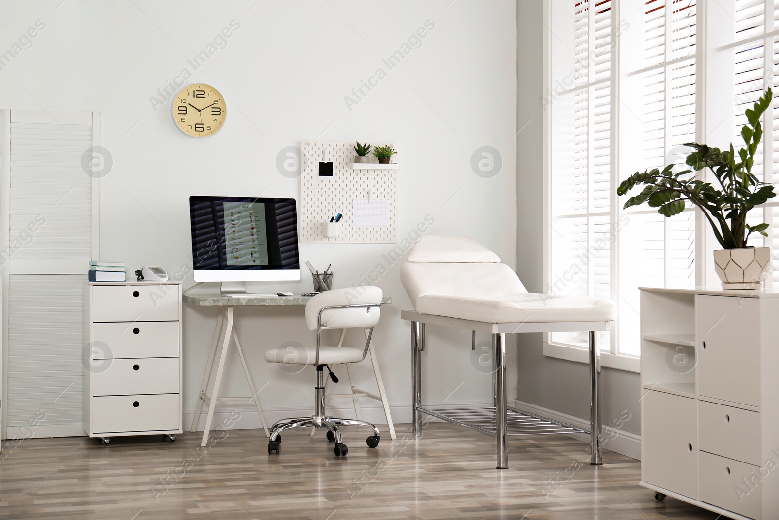 Photo of Modern medical office interior with computer and examination table