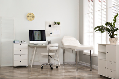 Modern medical office interior with computer and examination table