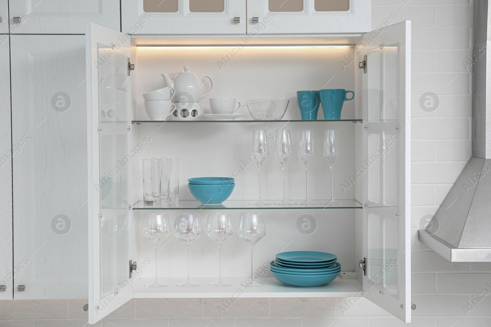 Photo of Open cabinet with different clean dishware in kitchen