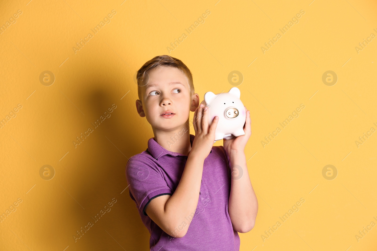 Photo of Little boy with piggy bank on color background