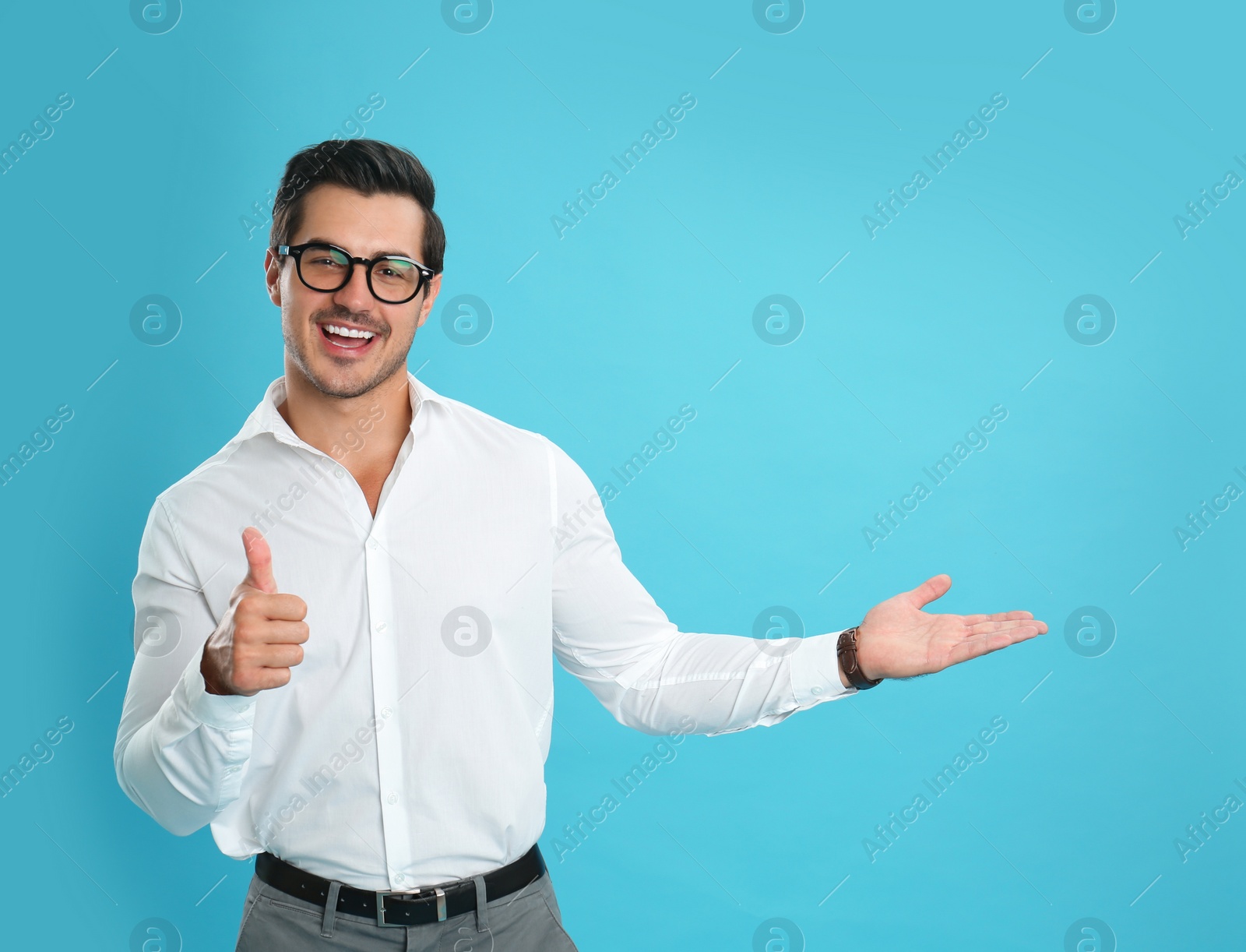 Photo of Young male teacher with glasses on light blue background. Space for text