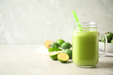 Fresh feijoa smoothie in mason jar on light table, closeup. Space for text