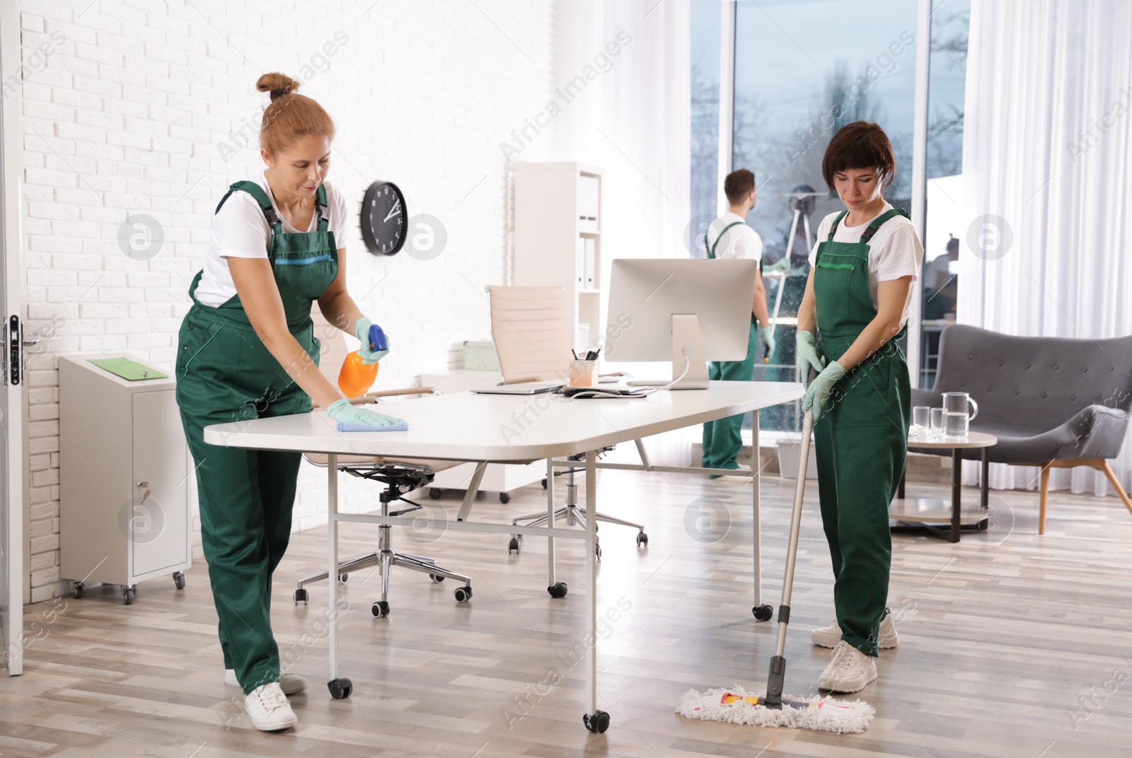 Photo of Team of professional janitors working in modern office. Cleaning service