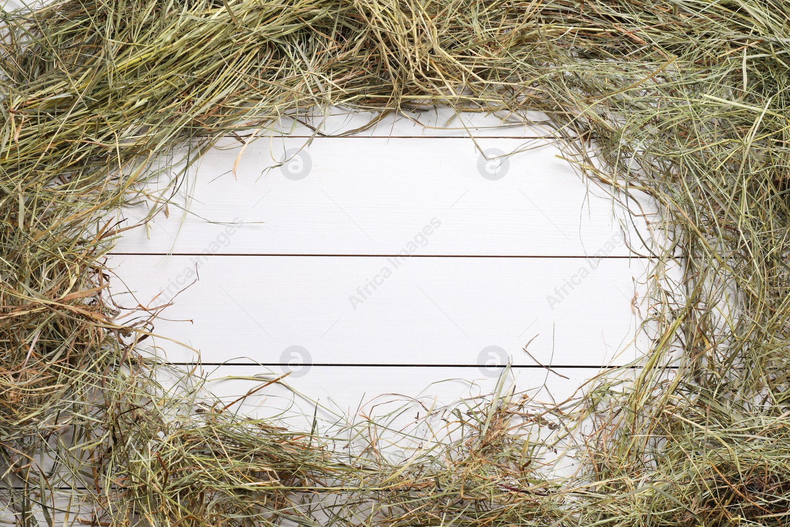 Photo of Frame made of dried hay on white wooden table, top view. Space for text