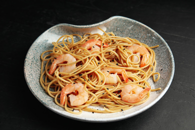 Photo of Plate of tasty buckwheat noodles with shrimps on black table