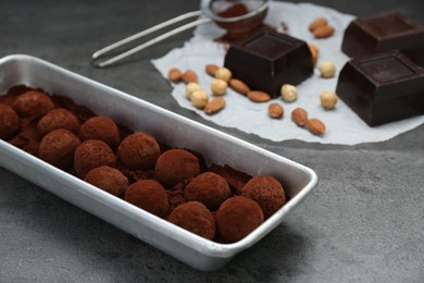 Delicious chocolate candies powdered with cocoa on grey table