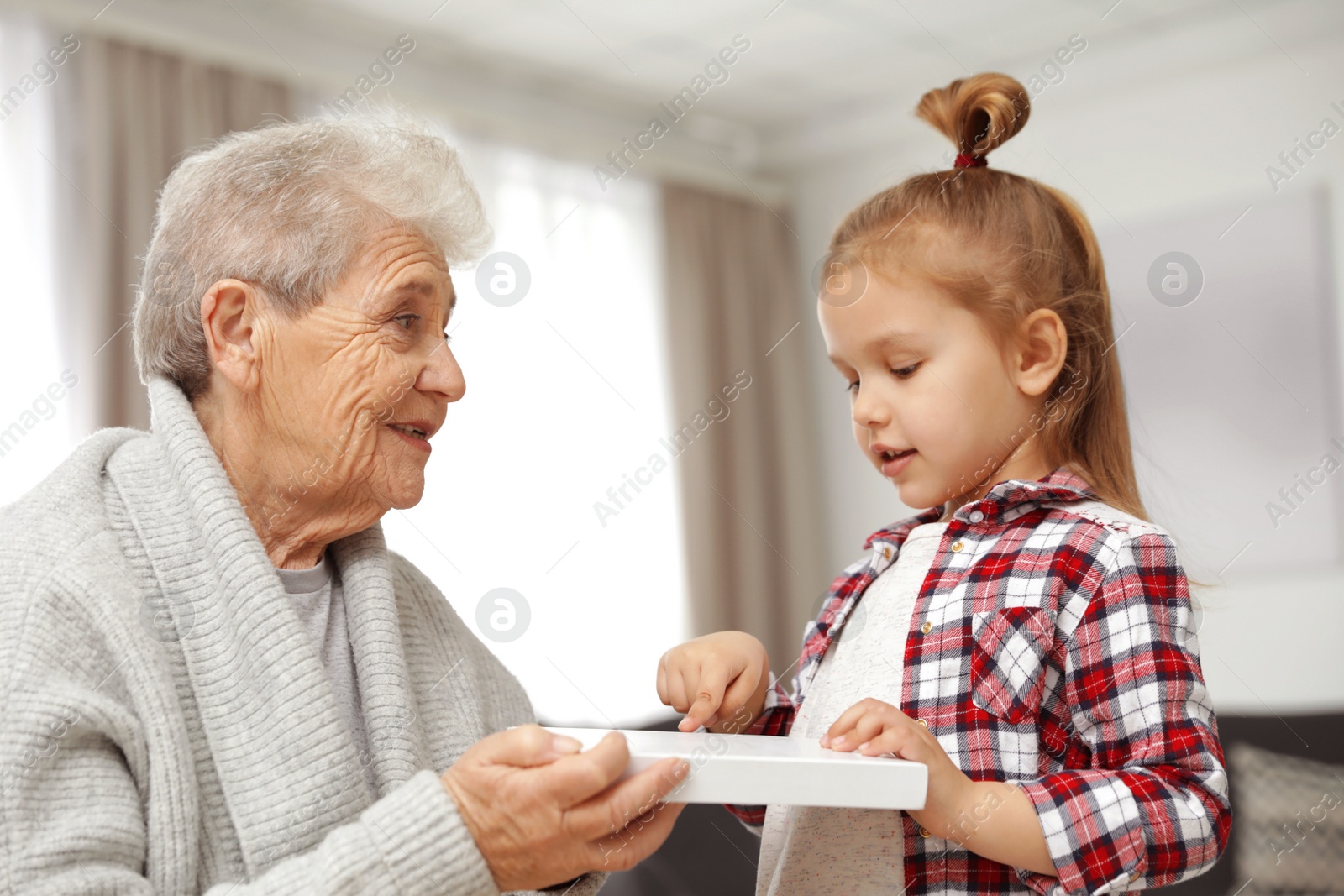 Photo of Cute girl and her grandmother with book at home