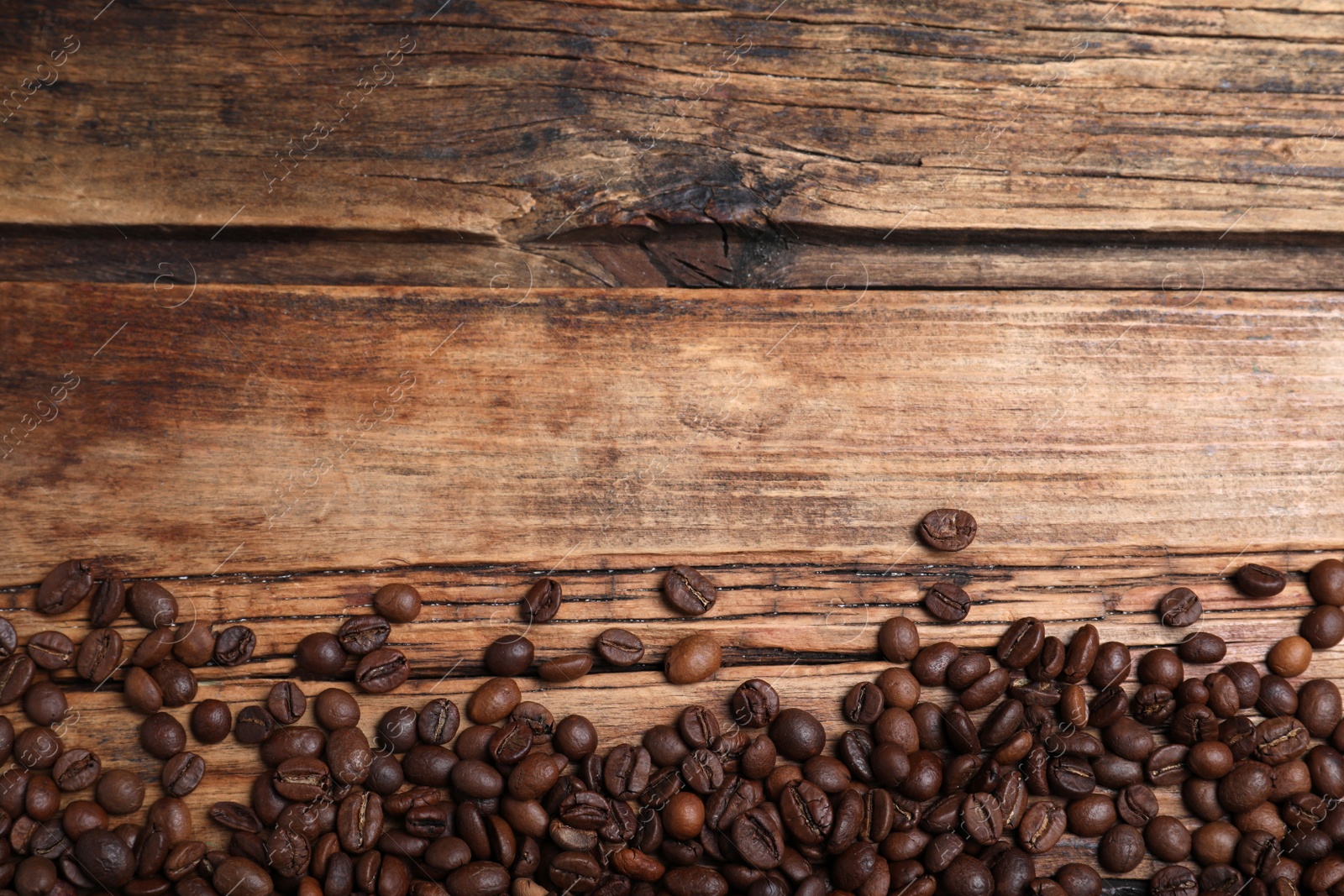 Photo of Many roasted coffee beans on wooden table, flat lay. Space for text