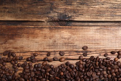 Photo of Many roasted coffee beans on wooden table, flat lay. Space for text