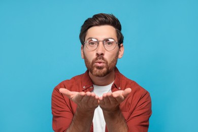 Handsome man blowing kiss on light blue background