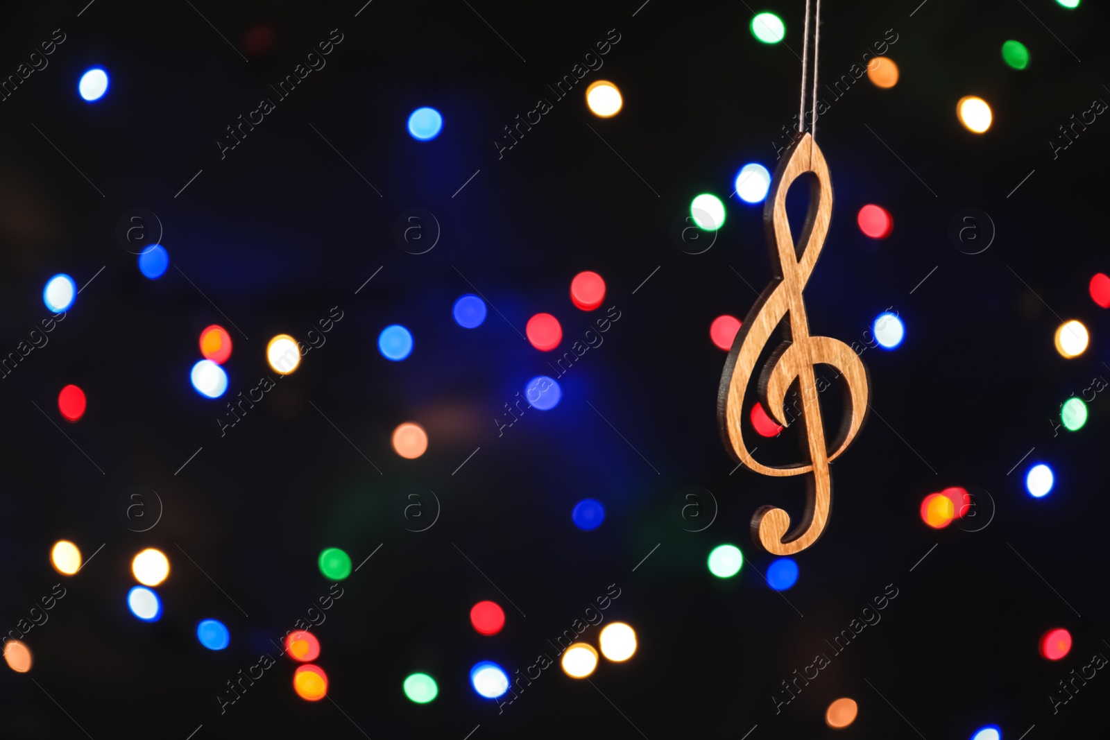 Photo of Wooden treble clef against defocused lights. Christmas music concept