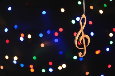 Wooden treble clef against defocused lights. Christmas music concept