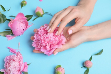 Woman holding beautiful peony flower on color background