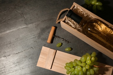 Photo of Flat lay composition with wooden crate and bottle of wine on grey table. Space for text