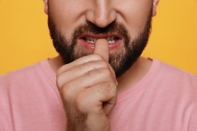 Photo of Man biting his nails on yellow background, closeup. Bad habit