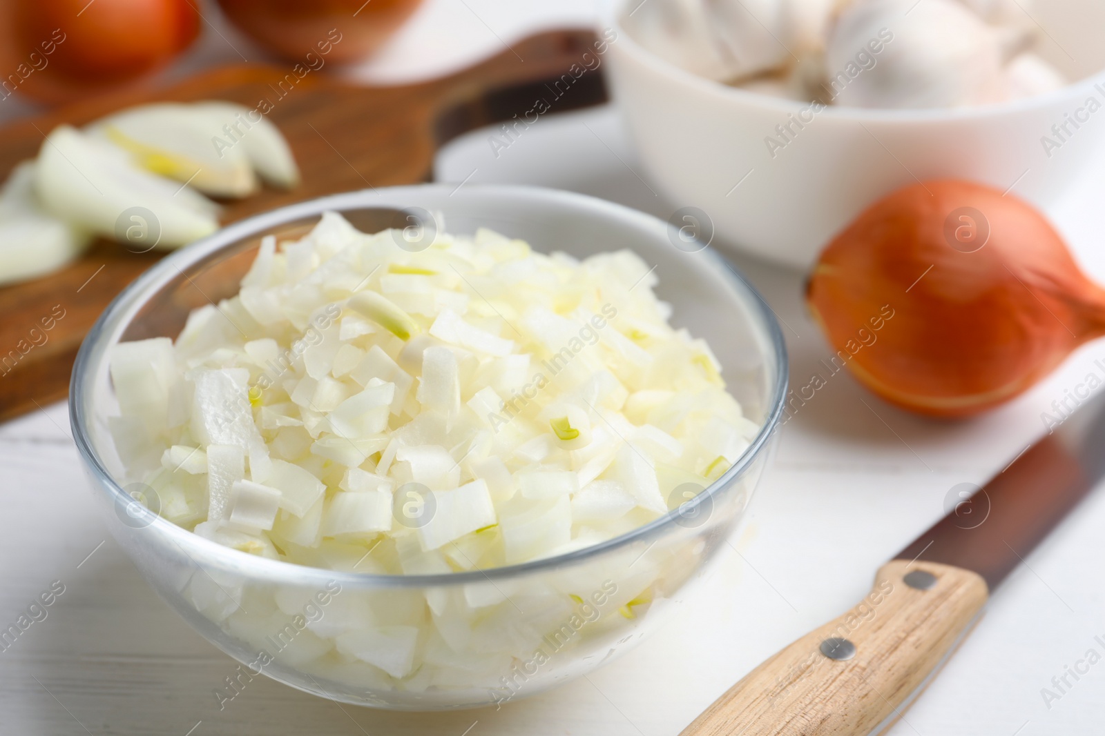 Photo of Chopped onion in bowl on white wooden table
