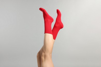 Photo of Woman in stylish red socks on light grey background, closeup