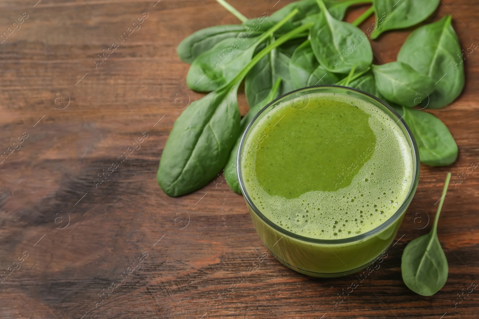 Photo of Glass with delicious detox juice and spinach on wooden background