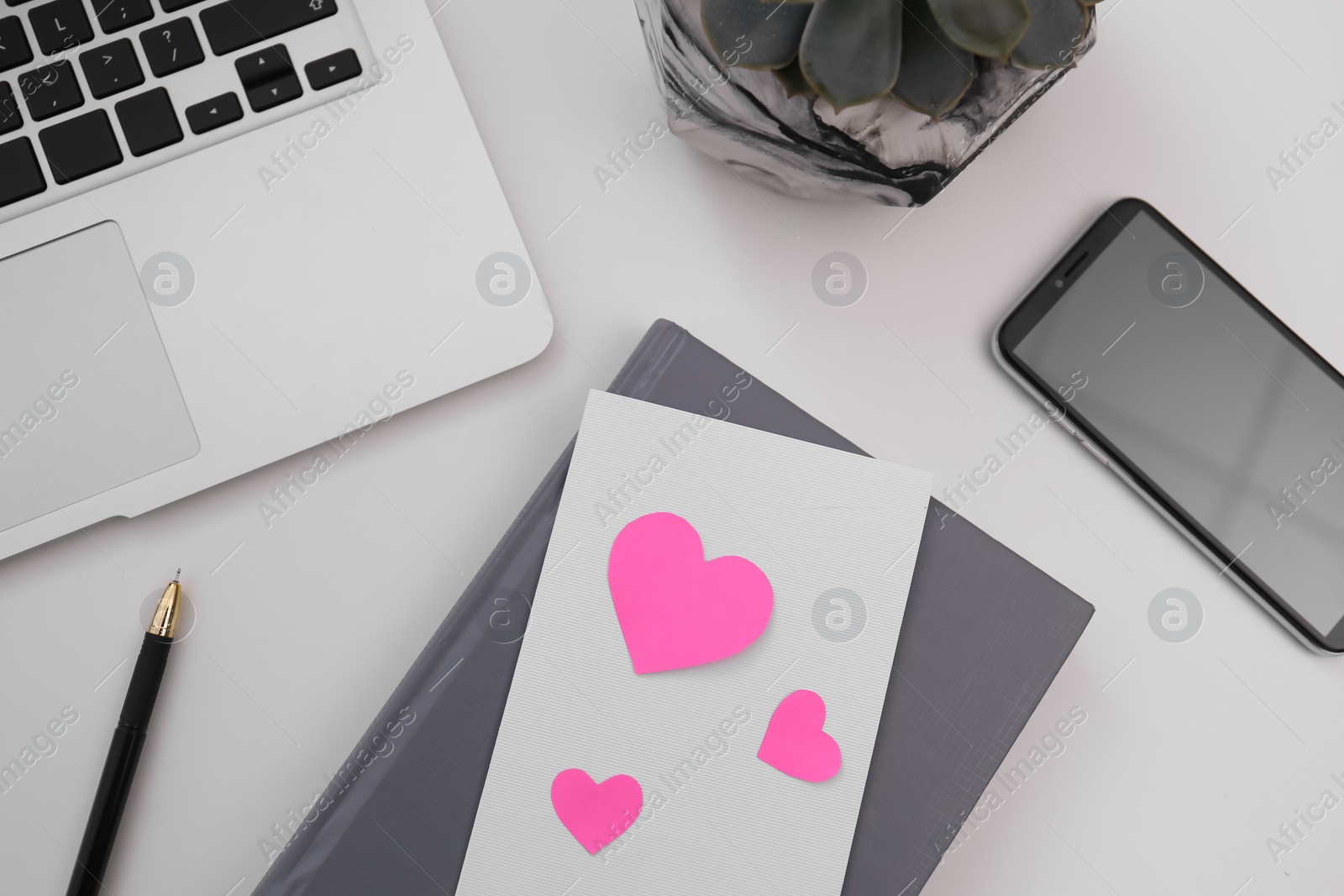 Photo of Greeting card with hearts at workplace, flat lay. Valentine's Day celebration