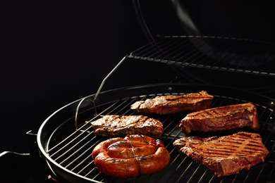 Photo of Fresh grilled tasty meat steaks and sausage on barbecue grate