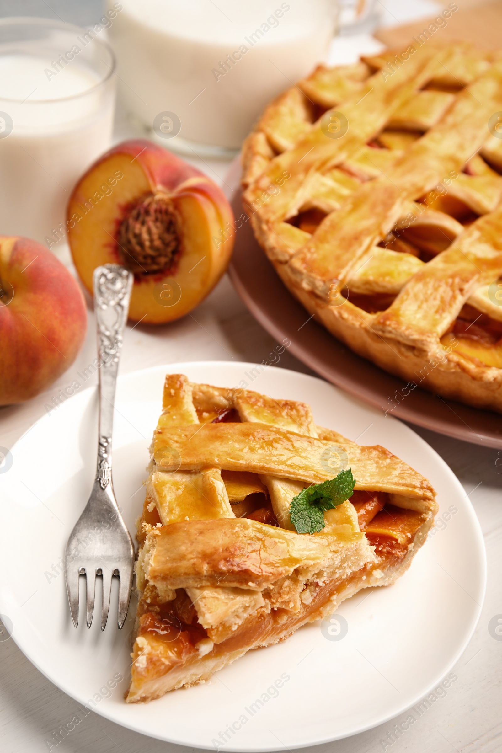Photo of Piece of delicious fresh peach pie served on white wooden table