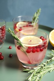 Photo of Tasty refreshing cranberry cocktail with rosemary on table