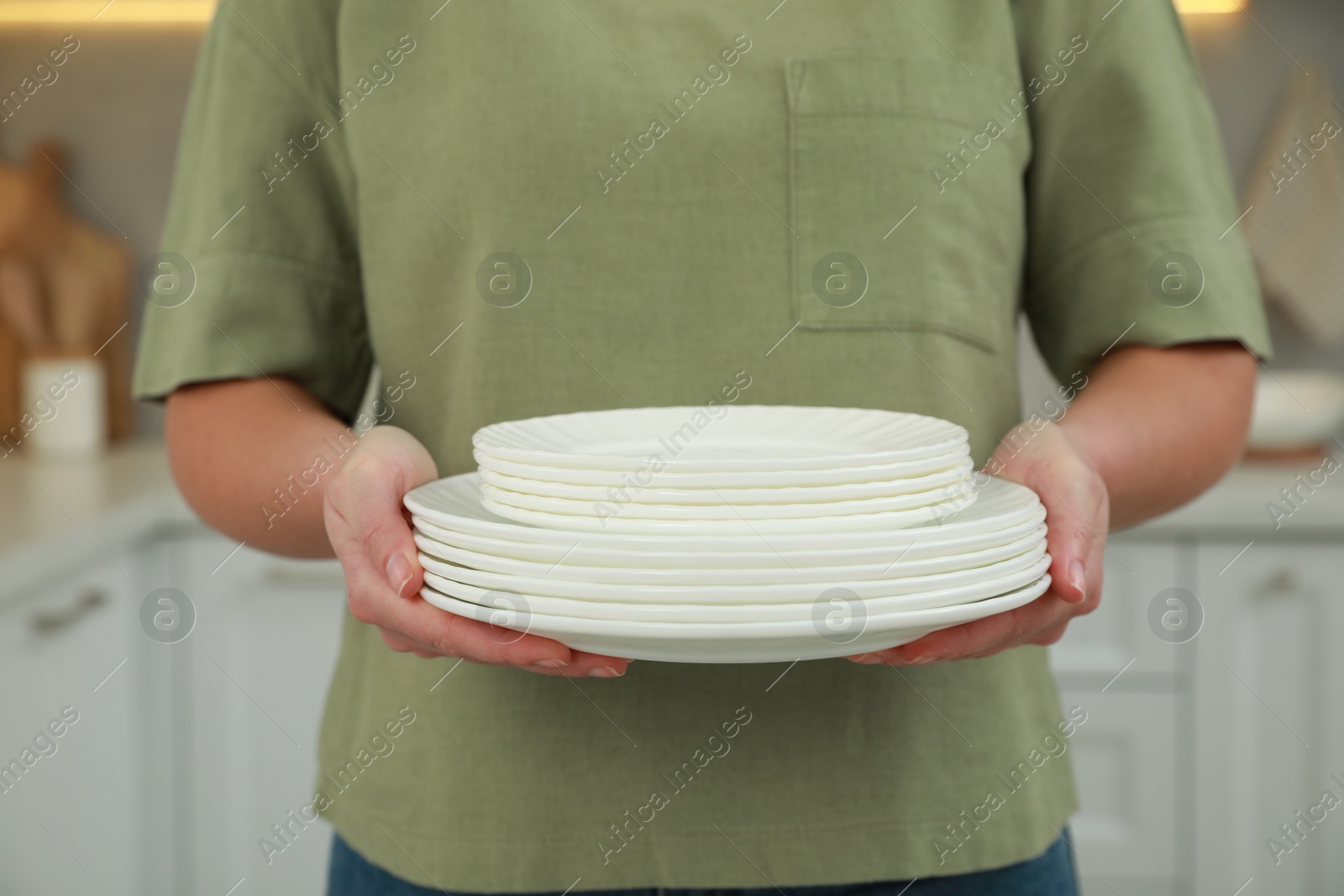 Photo of Woman holding plates in kitchen, closeup view