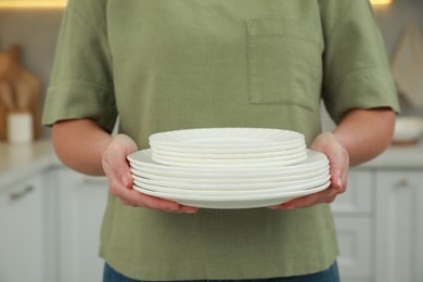 Woman holding plates in kitchen, closeup view