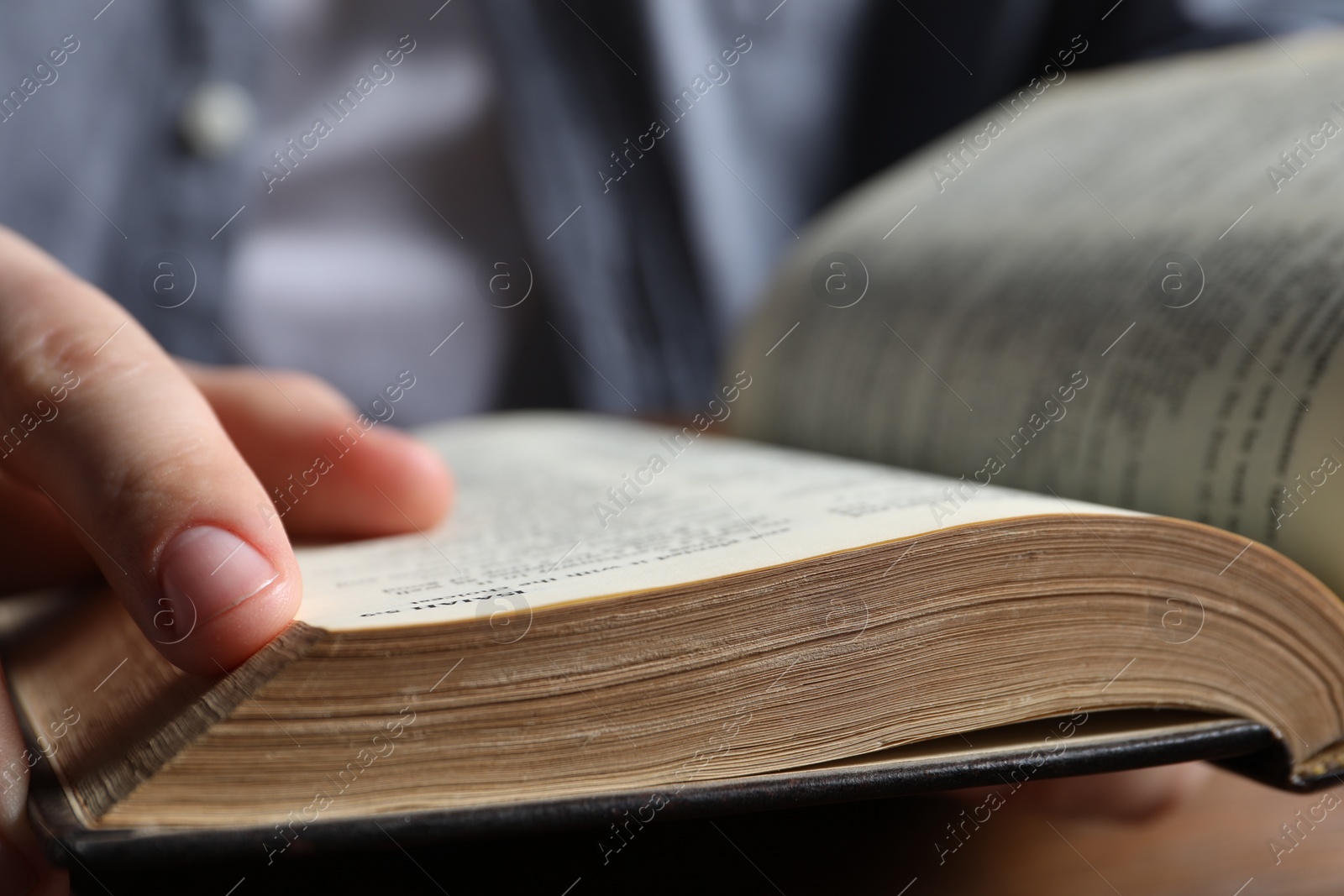 Photo of Man reading holy Bible at wooden table, closeup