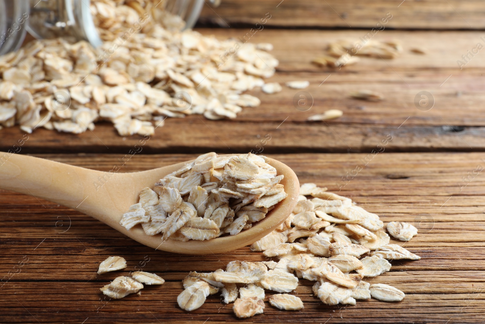 Photo of Raw oatmeal and spoon on wooden table, closeup