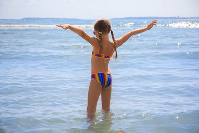 Little girl having fun in sea on sunny day. Beach holiday