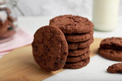 Photo of Tasty chocolate cookies on wooden board, closeup