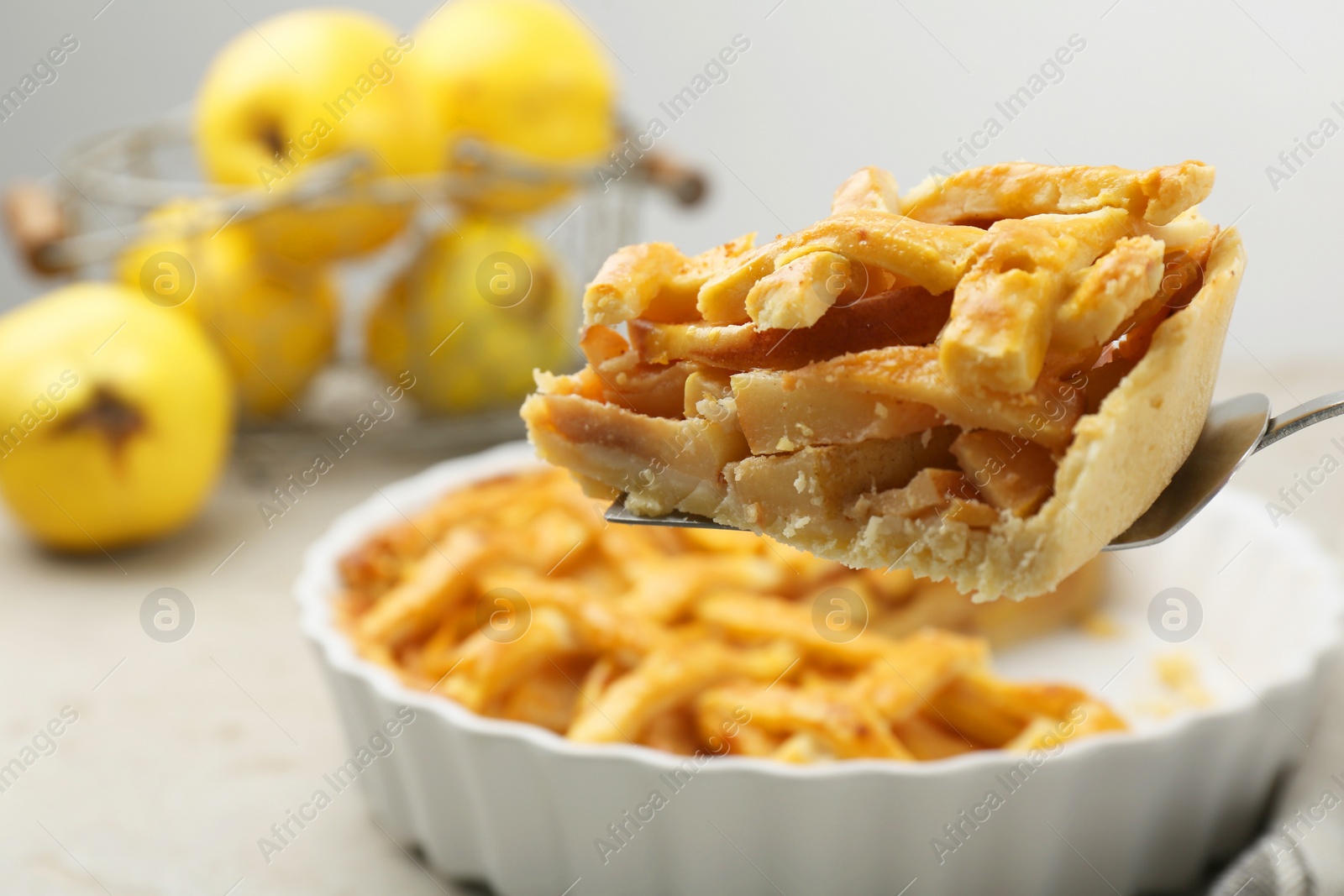 Photo of Cake server with piece of tasty homemade quince pie on light table, closeup