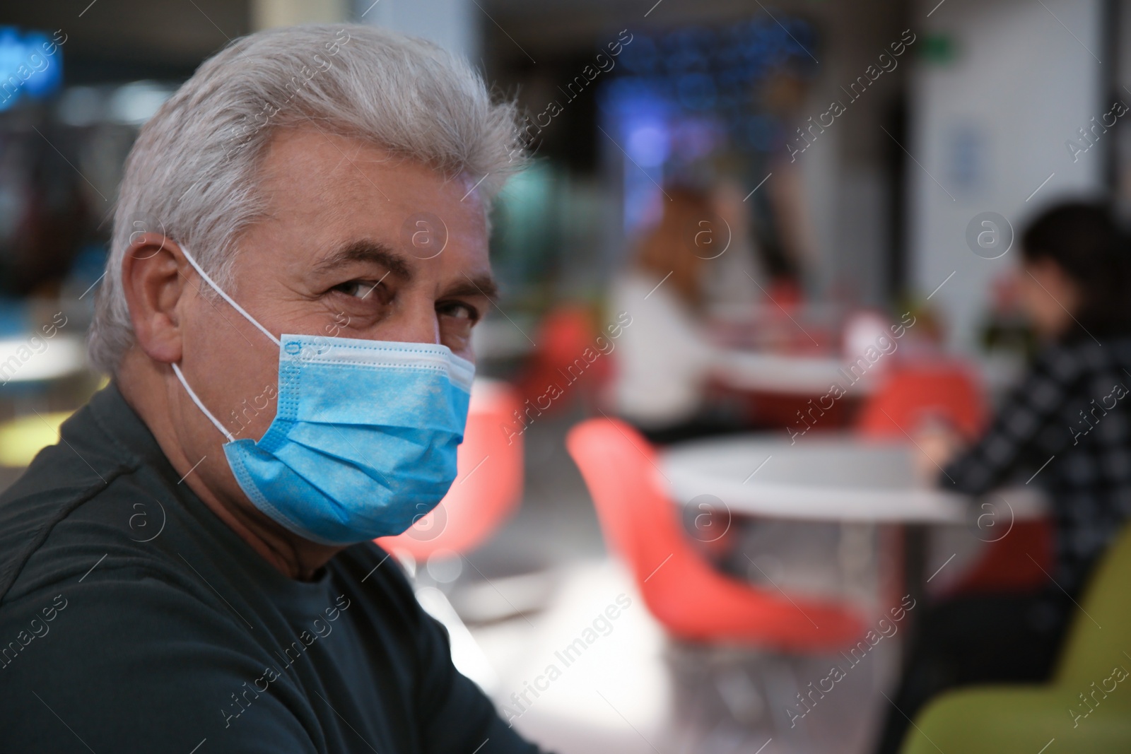 Photo of Senior man with medical mask in cafe. Virus protection