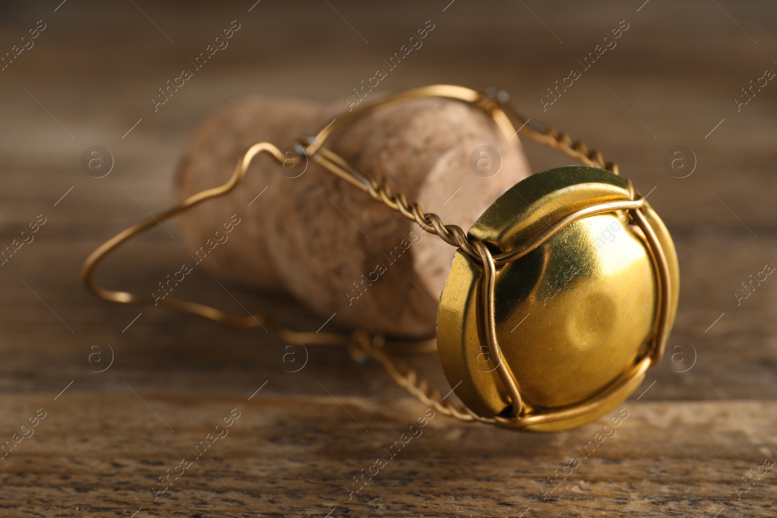 Photo of Cork of sparkling wine and muselet cap on wooden table, closeup