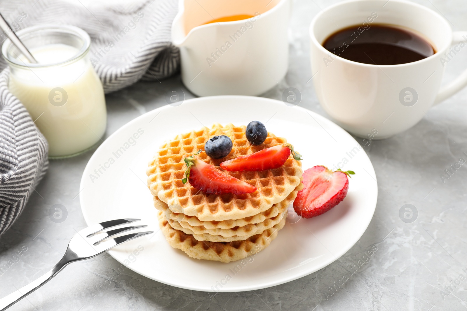 Photo of Tasty breakfast with wafers served on light grey marble table