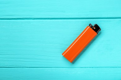 Photo of Stylish small pocket lighter on turquoise wooden background, top view. Space for text