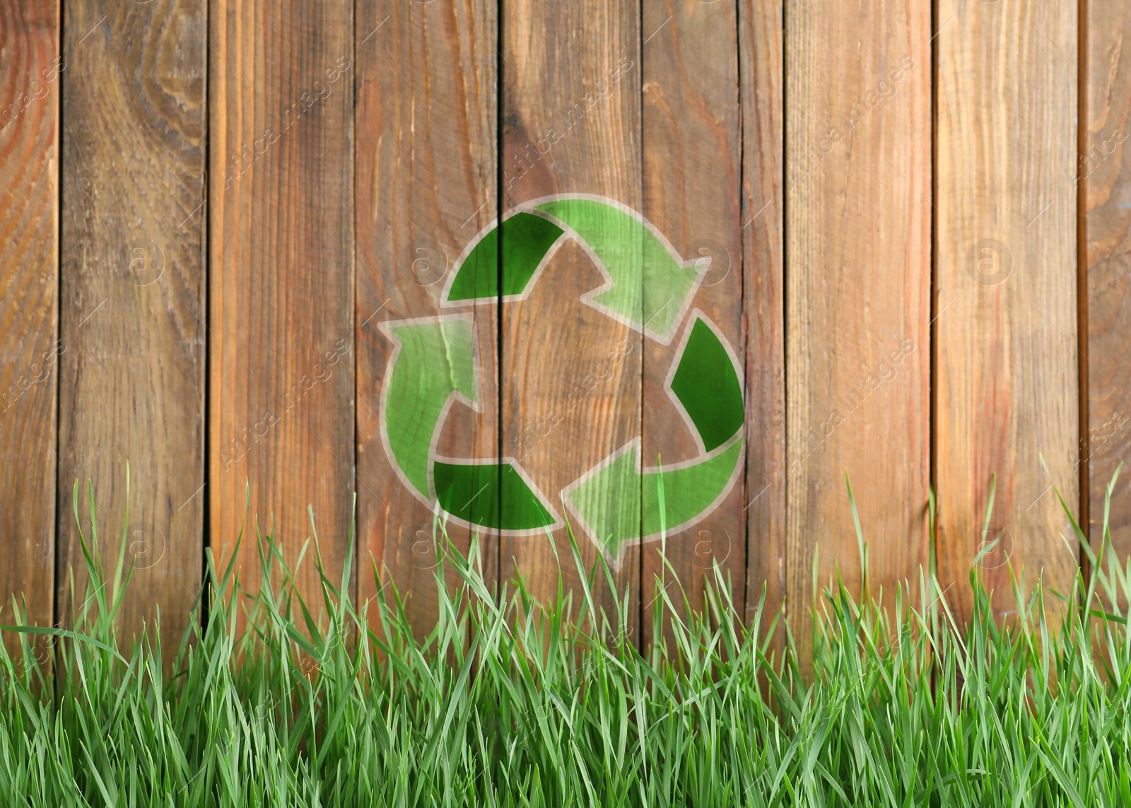 Image of Green grass and illustration of recycling symbol on wooden fence