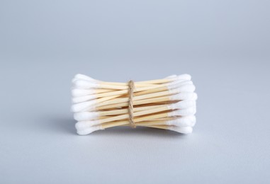 Bunch of wooden cotton buds on light grey background