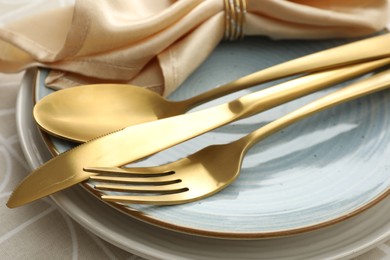 Photo of Stylish setting with cutlery, plates and napkin on table, closeup