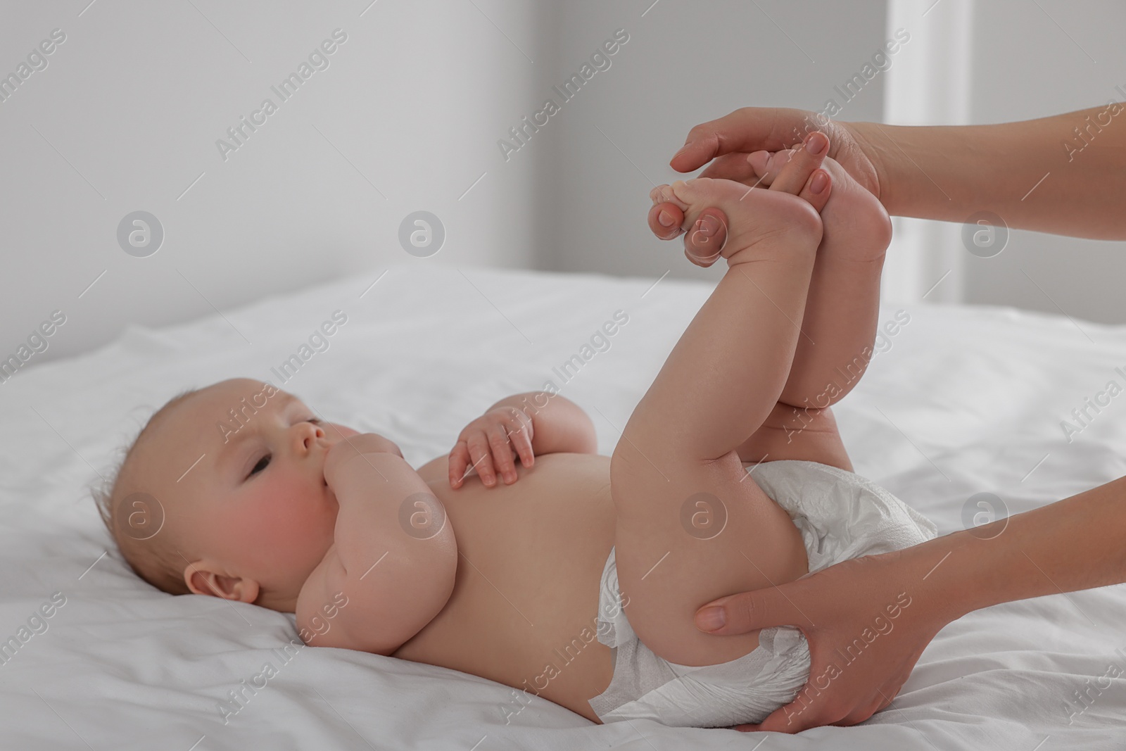 Photo of Mother changing her newborn baby's diaper on bed at home, closeup