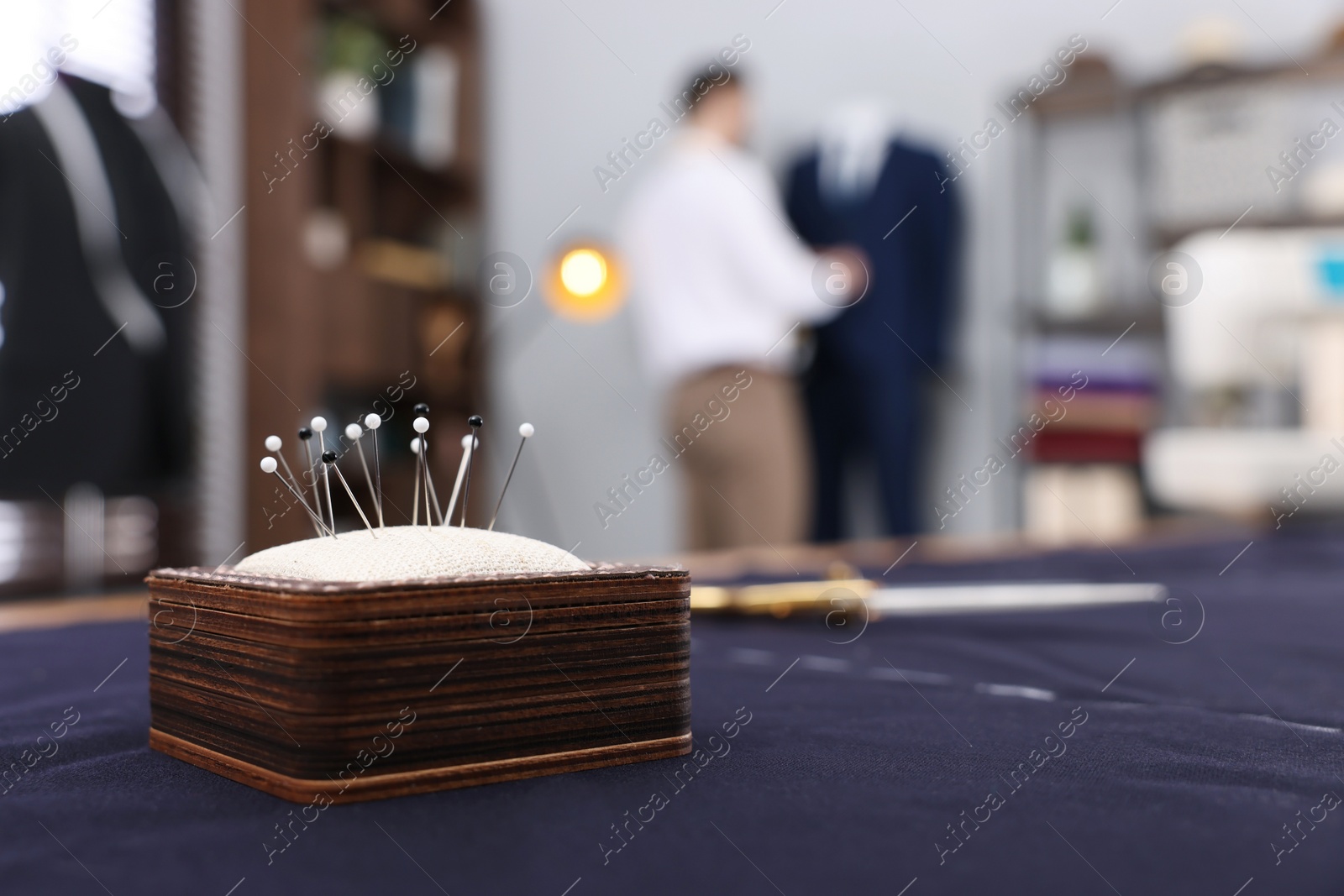 Photo of Dressmaker working in atelier, focus on pin cushion. Space for text