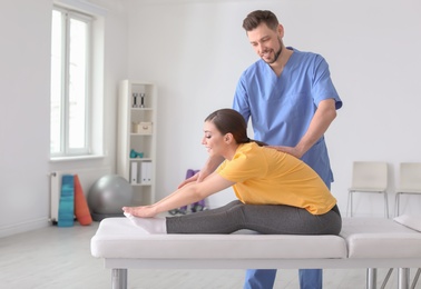 Photo of Physiotherapist working with female patient in clinic