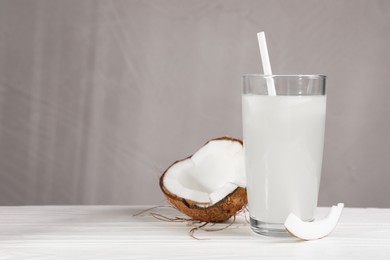 Photo of Glass of coconut water and nut on white wooden table. Space for text