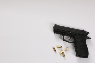 Handgun and bullets on white background, flat lay. Space for text
