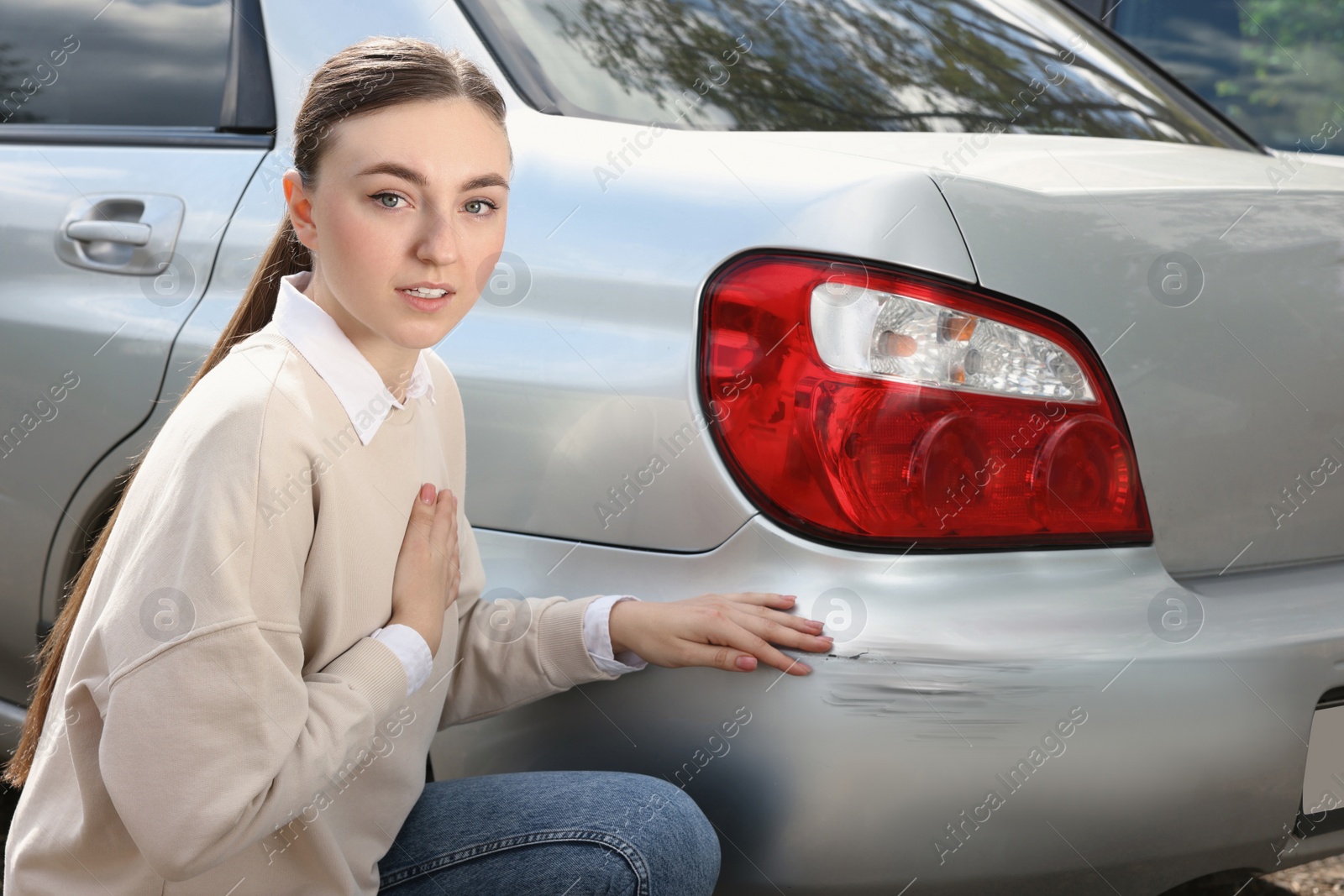 Photo of Stressed woman near car with scratch outdoors