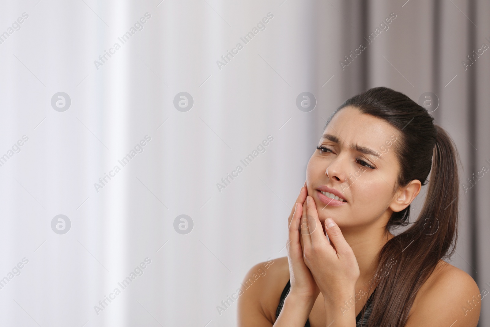 Photo of Young woman with sensitive teeth indoors. Space for text